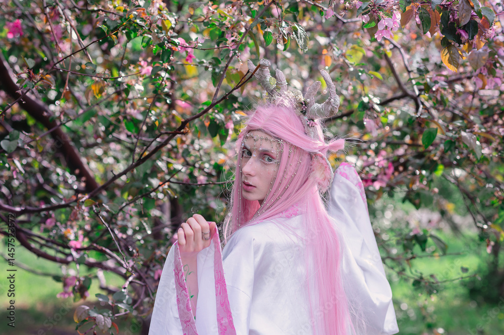Deer dryad girl against the background of a blooming pink apple tree