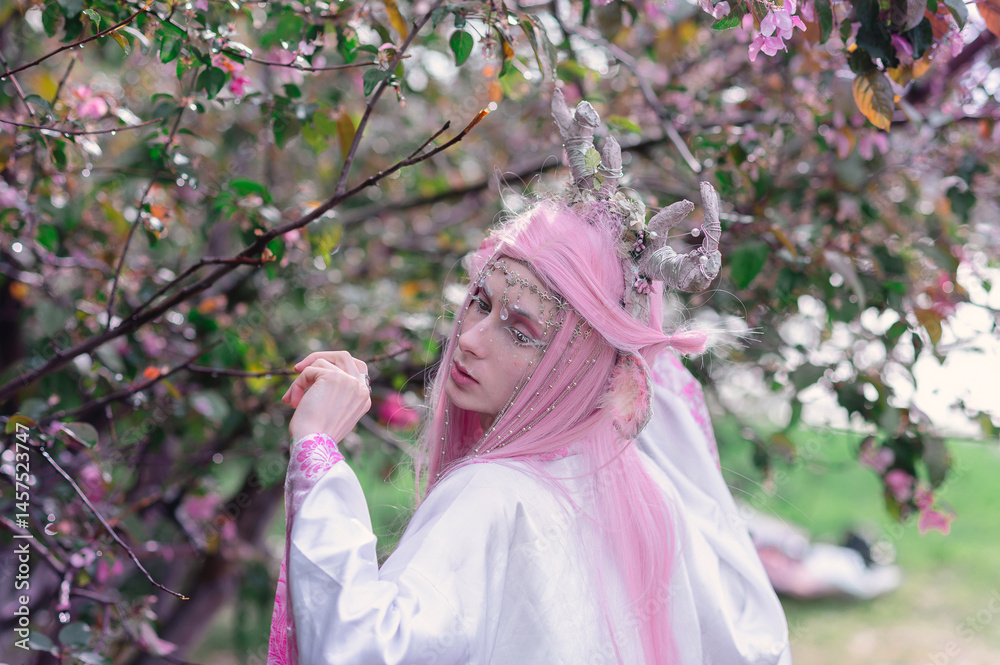 Deer dryad girl against the background of a blooming pink apple tree