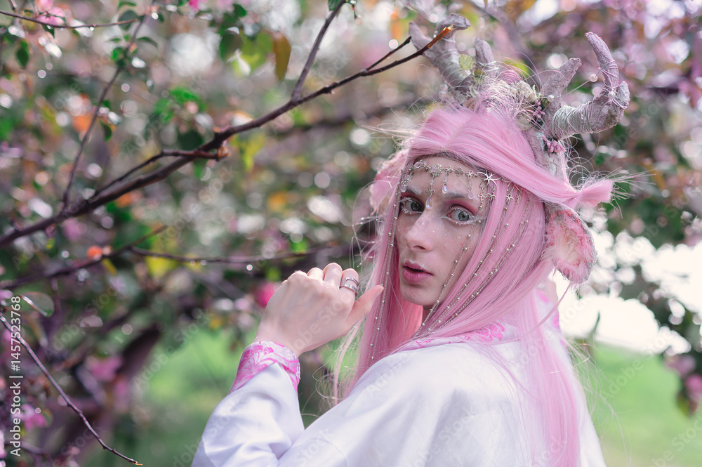 Deer dryad girl against the background of a blooming pink apple tree
