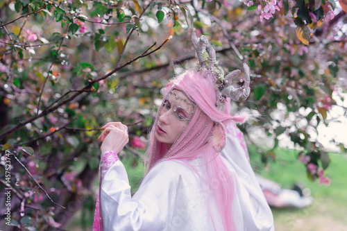 Obraz na płótnie Deer dryad girl against the background of a blooming pink apple tree w salonie