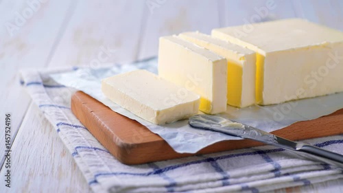 cut block butter on a white wooden table. Stick of butter, cut. Tasty butter and knife on a white kitchen table.