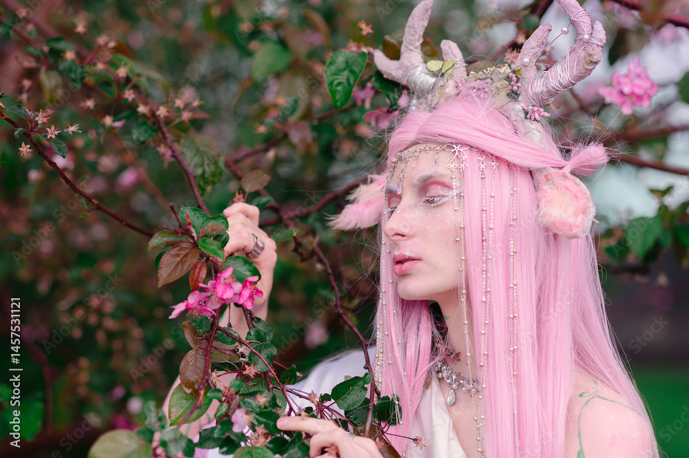 Deer dryad girl against the background of a blooming pink apple tree