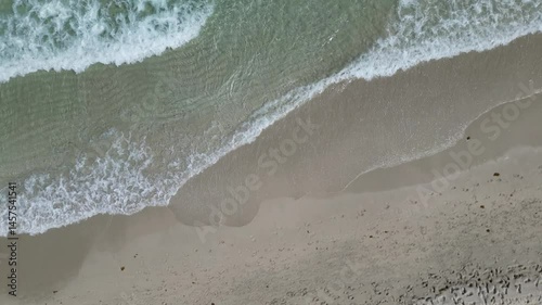 Drone shot of waves crashing on sandy beach