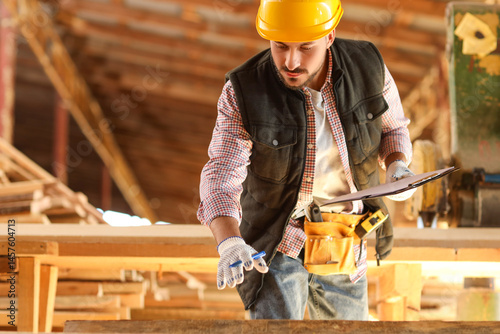 Young carpenter in hardhat ...