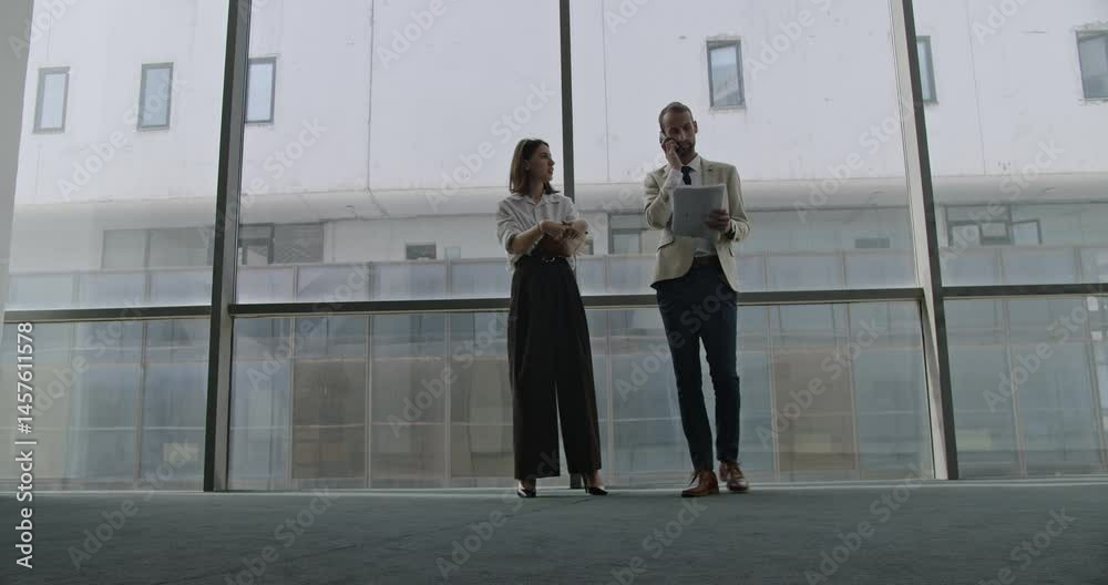 Business partners discussing in modern office space. Man and woman discussing a contract. Modern architecture. Business meeting. Business partners discussing in modern office space. Man and woman discussing a contract. Modern architecture. Business meeting.