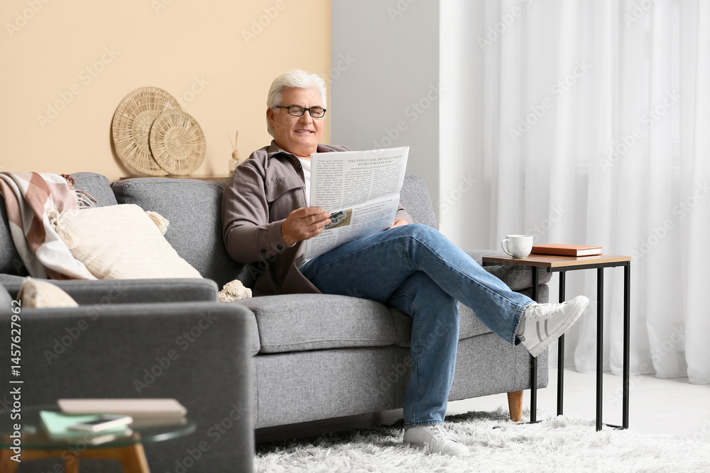 Handsome senior man reading newspaper and sitting on sofa in living room Handsome senior man reading newspaper and sitting on sofa in living room