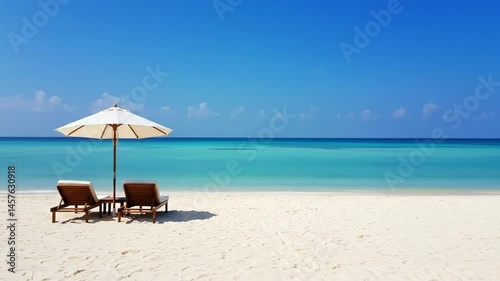 Two beach chairs and umbrella on sandy shore. photo