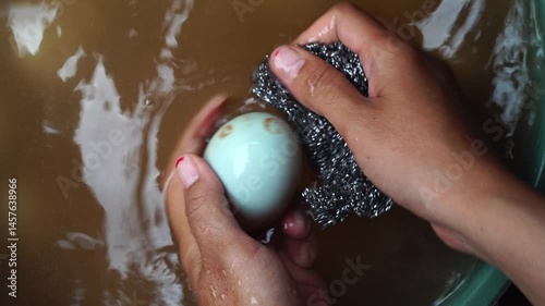 Woman's hands are rubbing and cleaning salted duck eggs