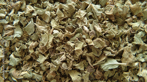 Top view of a textured pile of dried and chopped basil spice, symbolizing natural flavor, culinary tradition, and the essence of Mediterranean cooking in organic, earthy tones.

