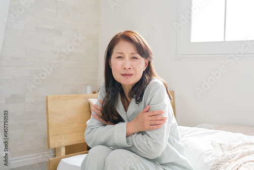寒気がするパジャマを着た中年の女性