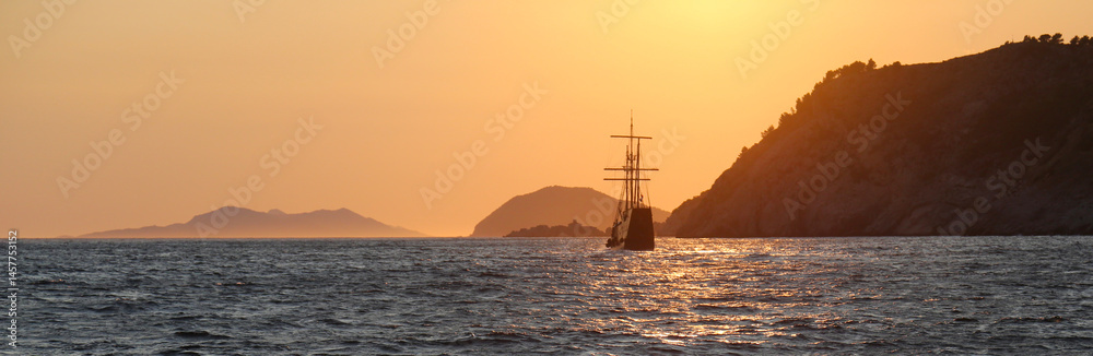 A tall ship sailing on the Adriatic sea at sunset.