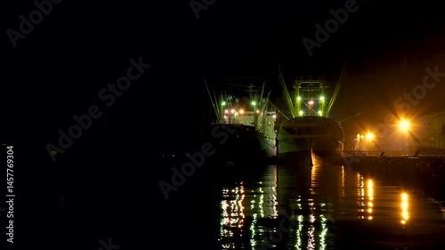 怪しい雰囲気がする無人の夜の港と停泊中の貨物船