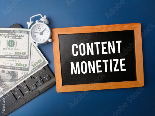 Top view wooden board and banknotes with the word CONTENT MONETIZE on a blue background