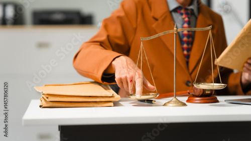 Obraz na płótnie An elderly Caucasian male lawyer works at his desk in a law firm, offering legal advice and business law services. A gavel and documents symbolize justice and professionalism w salonie