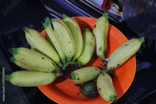 A bunch of ripe bananas are on an orange plate