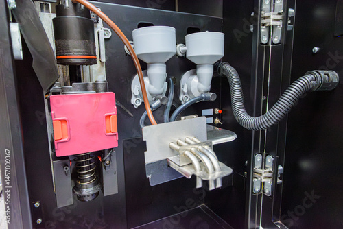Close-up of internal mechanical components of an automatic coffee machine, showing pistons, powder dispensers, tubing and dispensing spouts.

