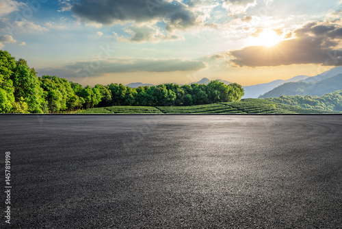 Fototapeta Naklejka Na Ścianę i Meble -  Empty asphalt road and green tea plantation with mountain natural landscape at sunset