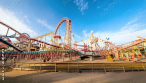A blurred amusement park scene captures the essence of thrill and excitement, featuring a roller coaster against a backdrop of a bright blue sky. A blurred scenery to be used as background.