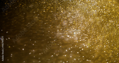 Luminous glimmering flare. Blur glitter. Defocused golden sparkling texture bright particles modern bokeh light glow abstract background.