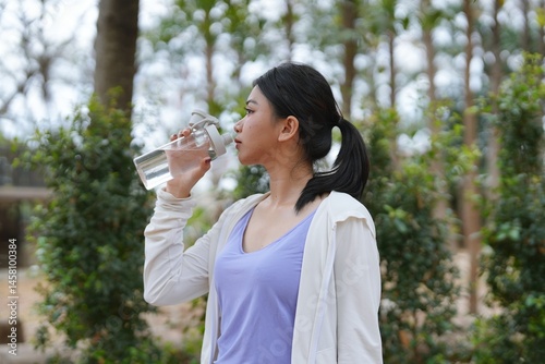 Asian women after running in outdoor Healthy active lifestyle beautiful girl drinking fresh water outdoor.