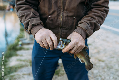 Closeup of man unhooking rainbow trout catch