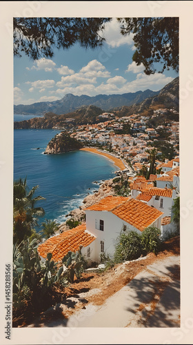 Coastal town nestled in a bay, whitewashed houses with terracotta roofs, overlooking a clear blue sea and mountains under a partly cloudy sky