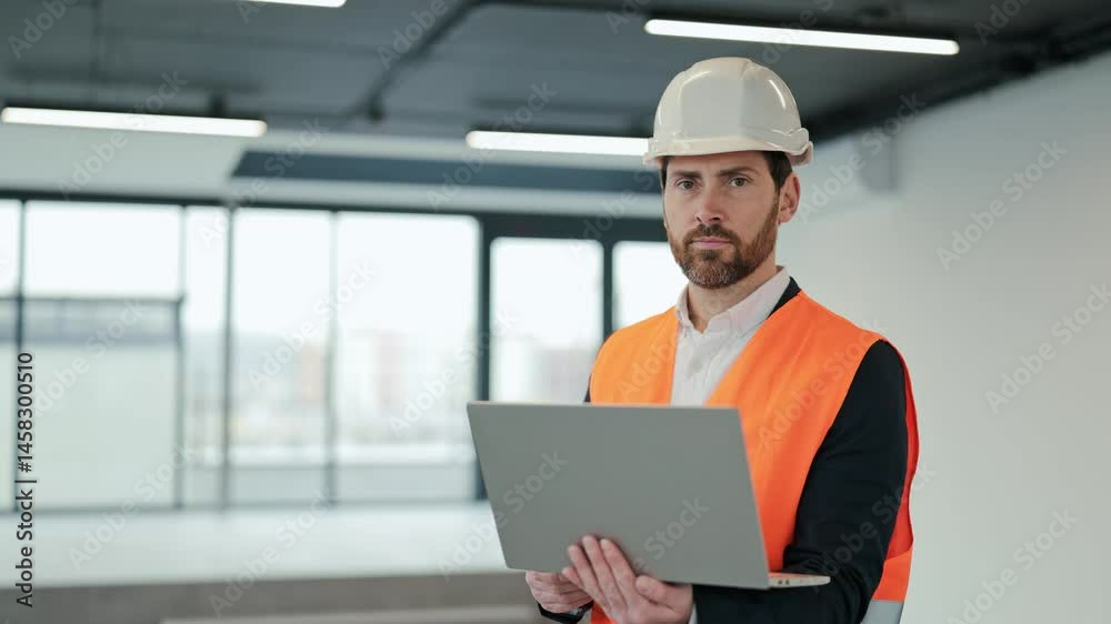 Successful engineer with laptop in empty office. Professional architect in formal wear with orange vest and white helmet. Successful engineer with laptop in empty office. Professional architect in formal wear with orange vest and white helmet.