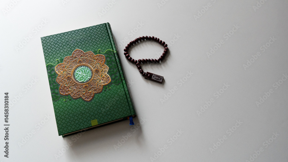 Obraz premium Holy Quran with Arabic calligraphy with wooden beads or tasbih on white background