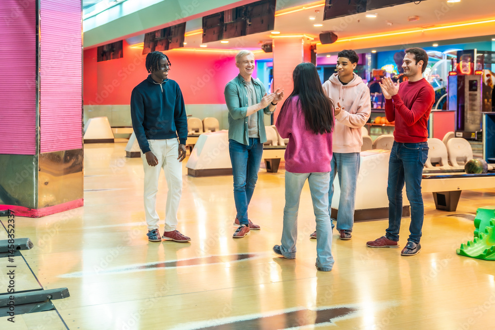 Happy friends congratulating each other after bowling game in entertainment center