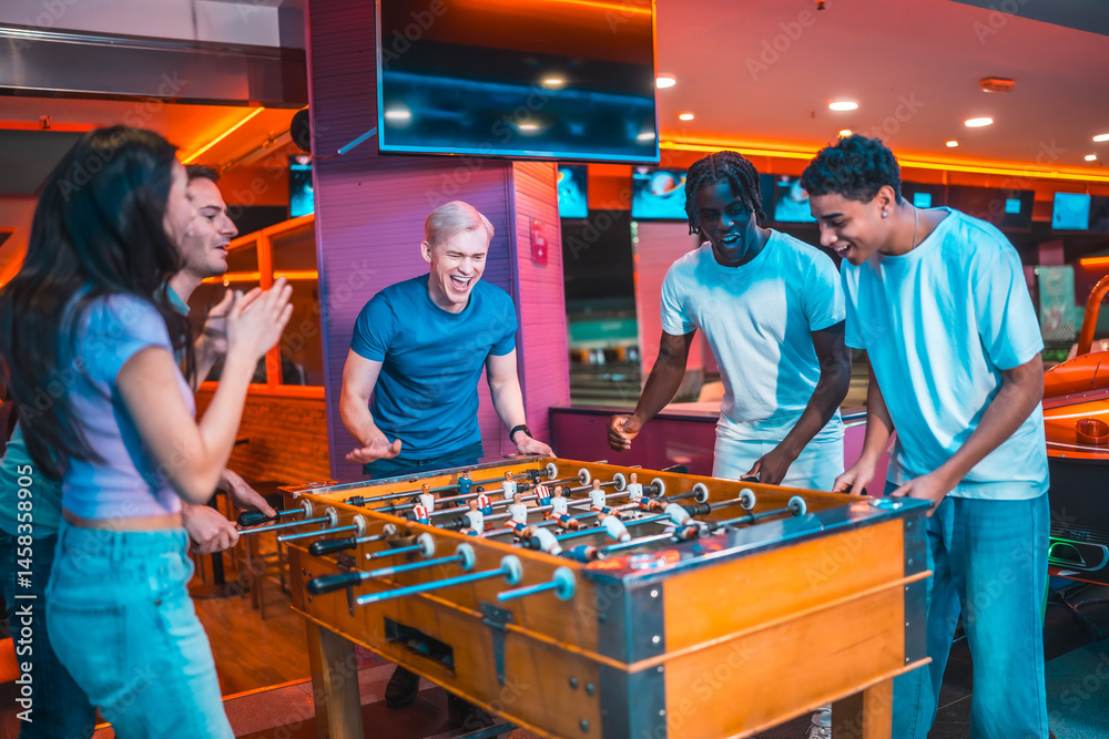 Enthusiastic friends playing foosball in entertainment center