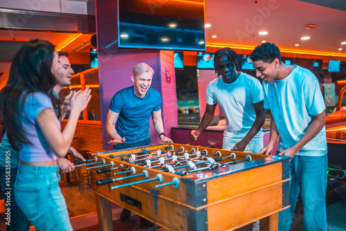 Obraz na płótnie Enthusiastic friends playing foosball in entertainment center w salonie