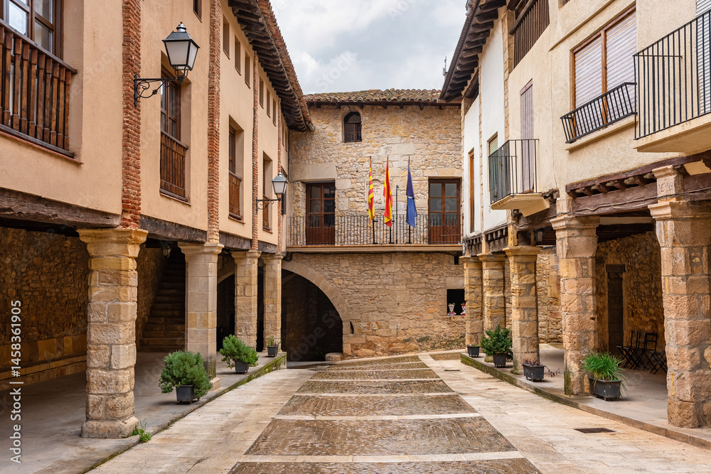 Street with arcades and stone columns in the tourist village of Rafales, Teruel, Spain.