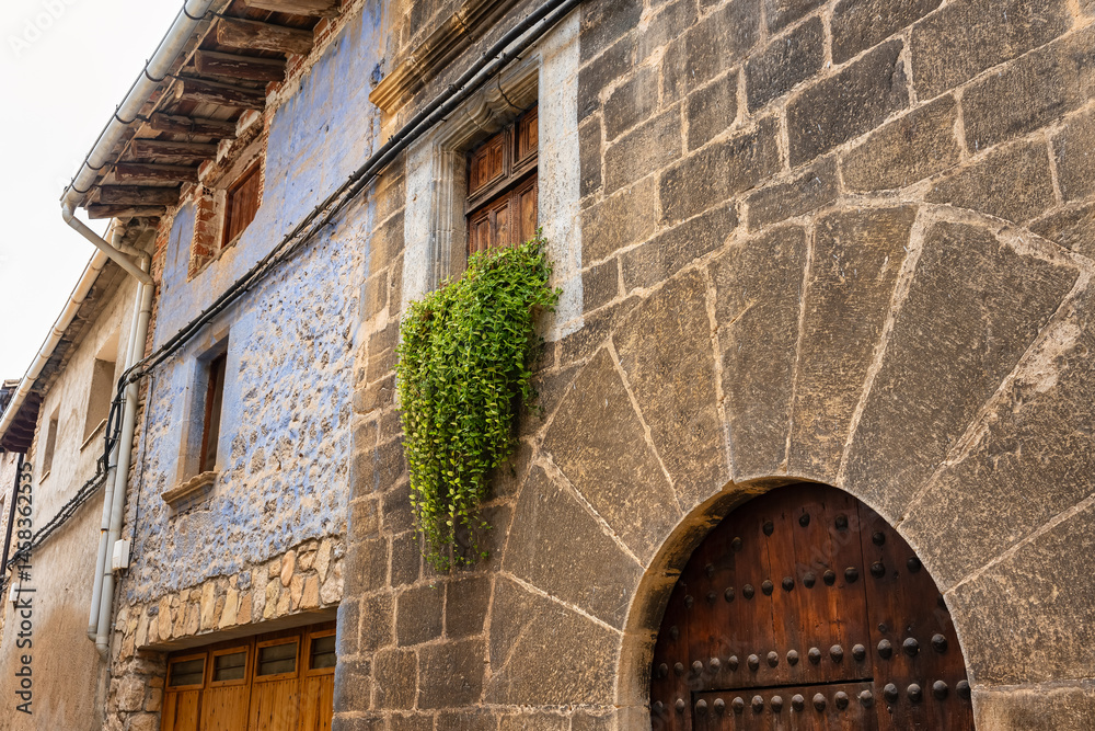 Facade of old stone houses with plants in the windows in the village of Rafales, Matarrana, Aragon.