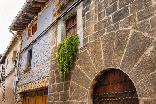 Facade of old stone houses with plants in the windows in the village of Rafales, Matarrana, Aragon.