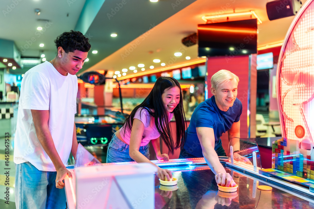 Multiethnic friends playing air hockey in an amusement arcade