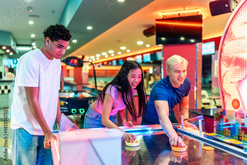 Obraz na płótnie Multiethnic friends playing air hockey in an amusement arcade w salonie