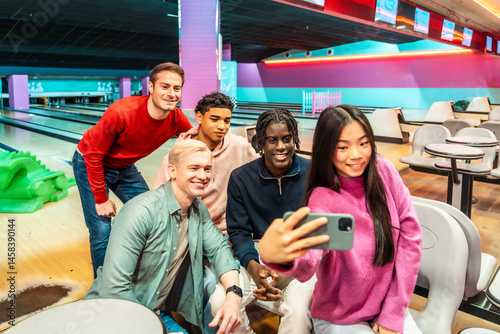Happy multiethnic friends taking selfie while bowling