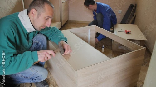 two men assembling furniture, two carpenters assemble kitchen furniture, assembly of new custom furniture