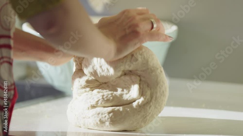 A home baker kneads pliant dough, preparing for fresh bread in a rustic kitchen.