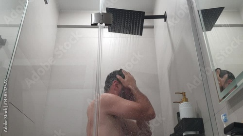 bearded man in the shower washes under cold water and freezes