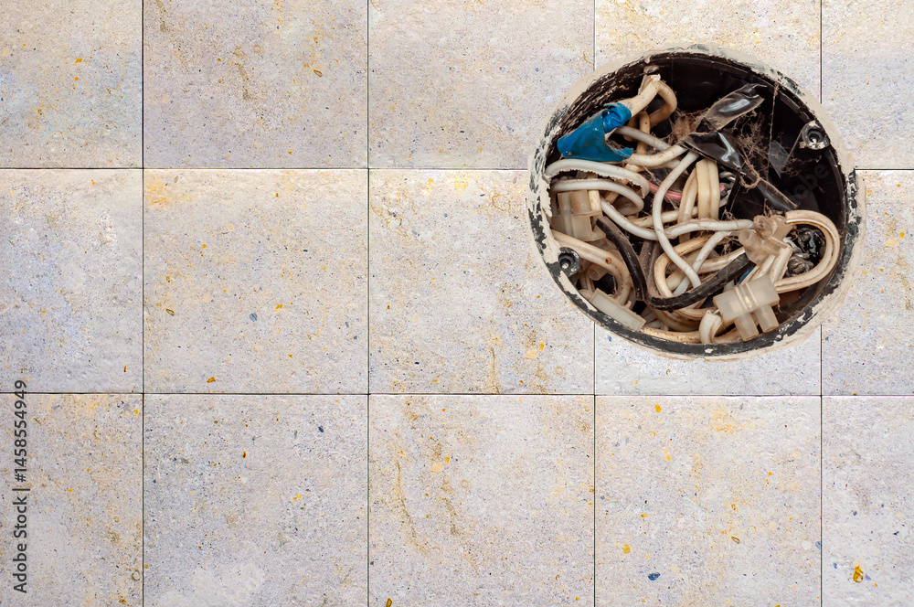 Open electrical box displays a tangle of wires and connectors set against a neutral tiled wall.