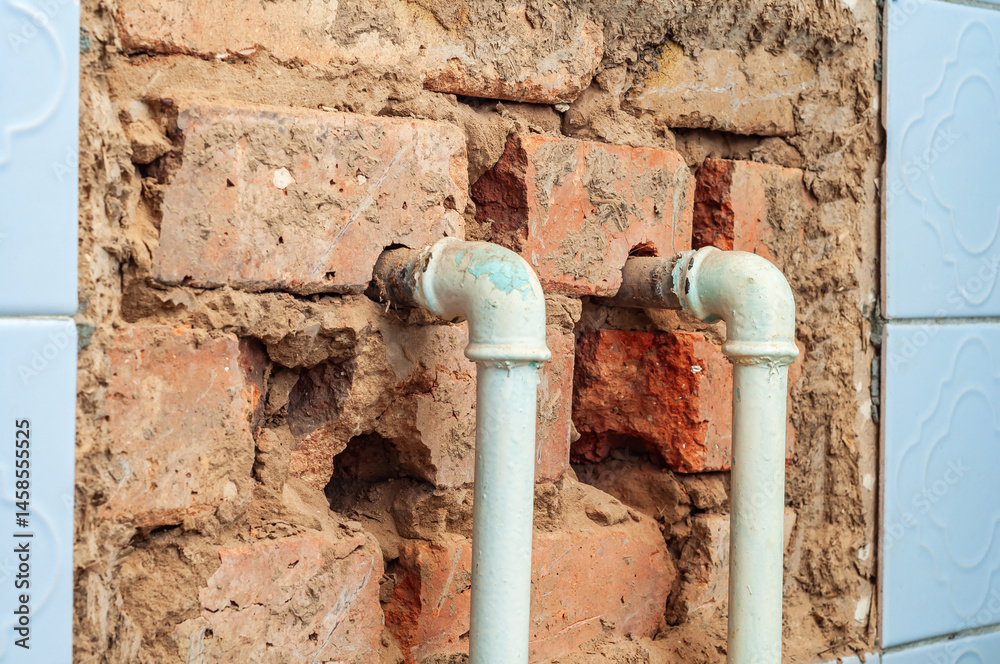 Close-up of exposed brick and pipes in a bathroom under renovation showing construction elements.