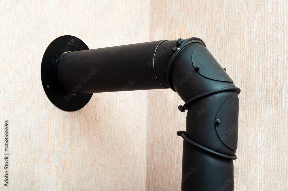 A black flue pipe makes a ninety degree turn near the wall for venting a wood stove.
