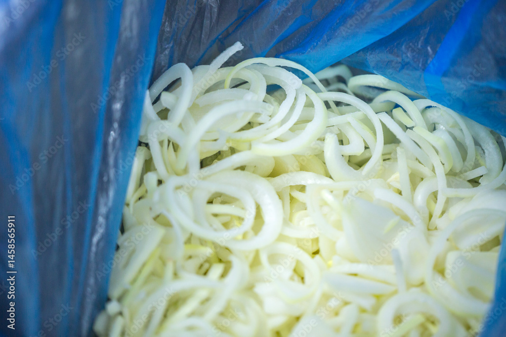 Close-up of shock-frozen onion rings and half-rings with a thin ice coating. Are prepared for retail packaging to ensure extended shelf life in supermarkets and maintain perishable harvest quality.