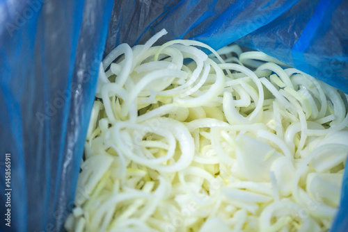 Obraz na płótnie Close-up of shock-frozen onion rings and half-rings with a thin ice coating. Are prepared for retail packaging to ensure extended shelf life in supermarkets and maintain perishable harvest quality. w salonie