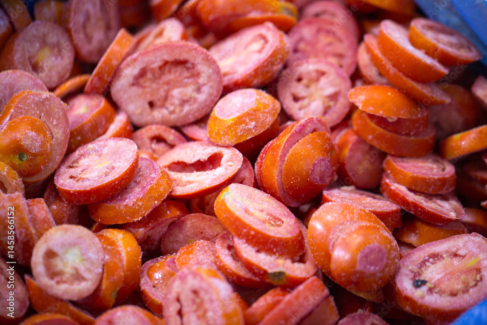 Close-up of shock-frozen sliced red tomatoes with a thin ice coating. Are prepared for retail packaging to ensure extended shelf life in supermarkets and maintain perishable harvest quality.