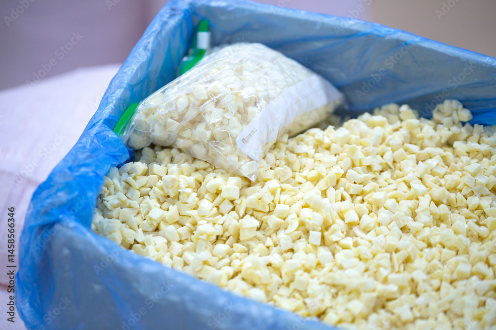 Close-up of shock-frozen chopped garlic pieces with a thin ice coating. Are prepared for retail packaging to ensure extended shelf life in supermarkets and maintain perishable harvest quality.