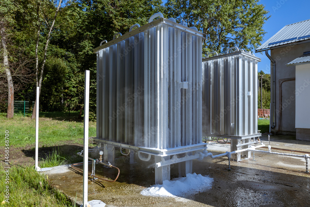 An oxygen station that produces and supplies medical oxygen to a hospital. The station includes cooling radiator fins, visible condensation vapor, and ice accumulating beneath and on the fins.