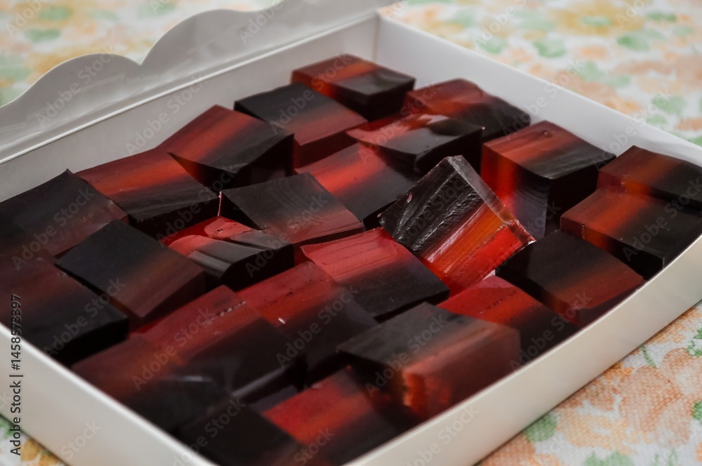 A box filled with layers of red and black jelly candies, a sweet and delicious treat.