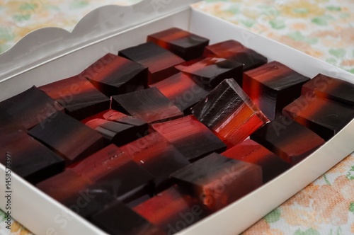 Obraz na płótnie A box filled with layers of red and black jelly candies, a sweet and delicious treat. w salonie